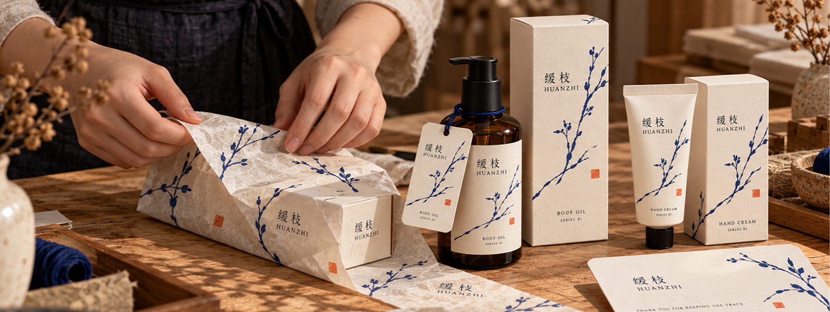身体护理油与护手霜共用暖象牙纸色、钴蓝枝线和朱砂橙印记，建立首发双品的统一识别。