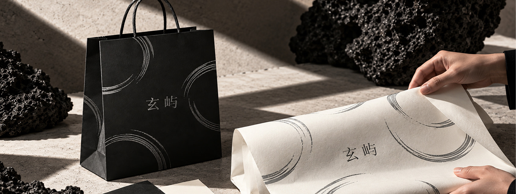 黑袋与暖白包装纸同场出现，展示不同底色下的共同品牌笔触。